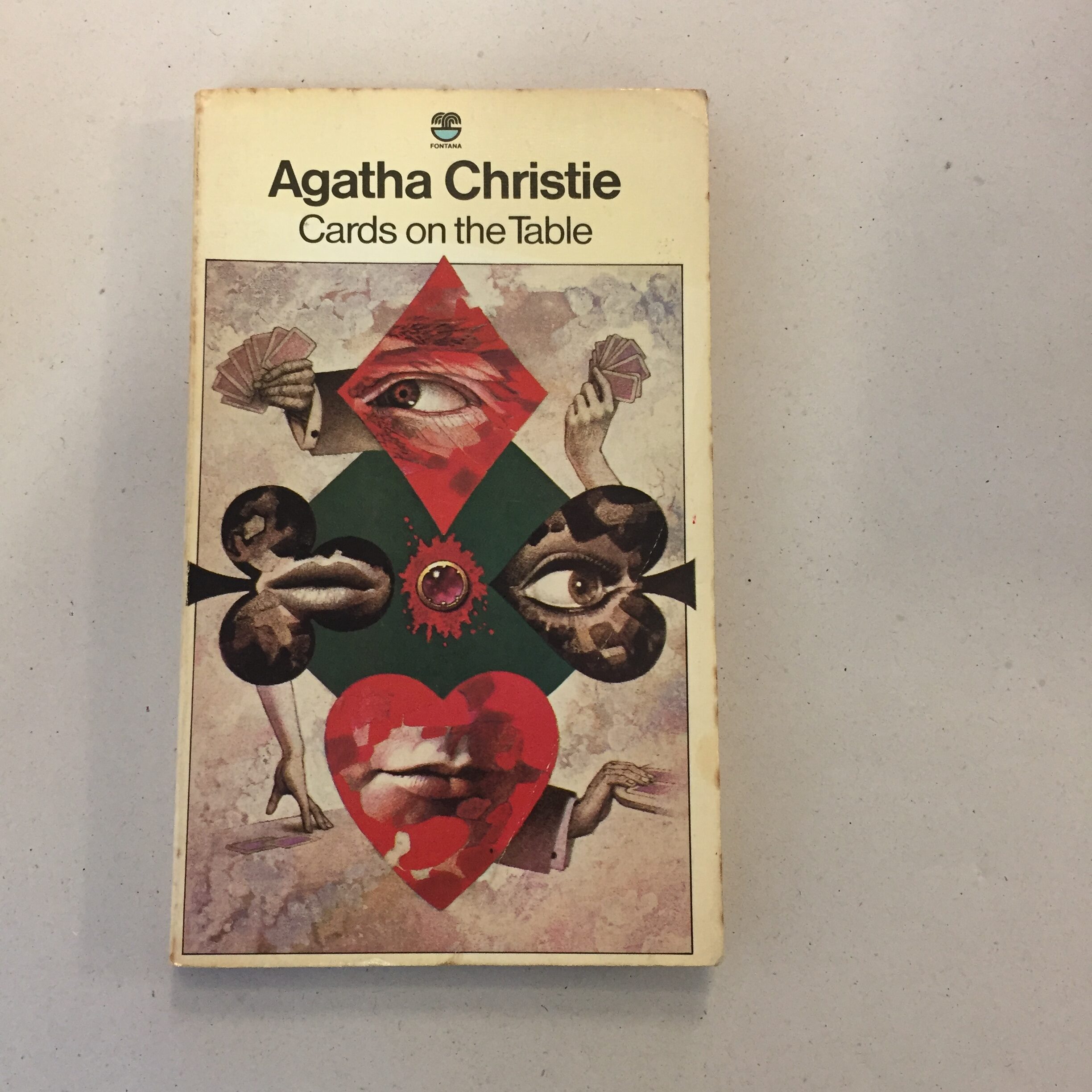 Fontana paperback edition of Agatha Christie's mystery novel Cards on the Table, featuring surrealist cover art by Tom Adams