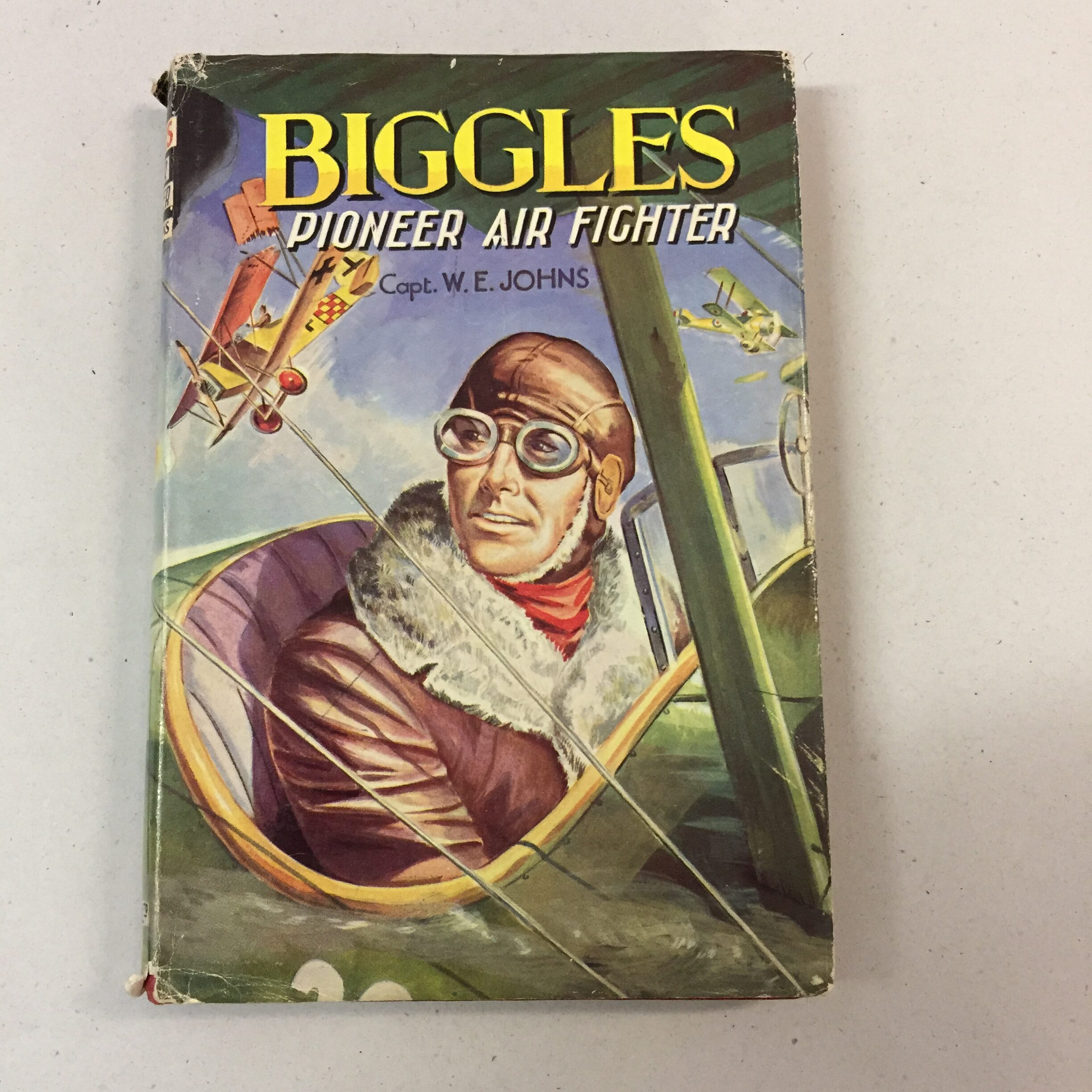Biggles: Pioneer Air Fighter by Captain W.E. Johns, featuring its original illustrated dust jacket with a pilot in a cockpit